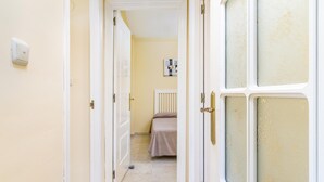 A narrow hallway with white doors leading to a bedroom. - Banana Beach (Marbella)