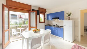 Una cocina moderna con armarios azules, un refrigerador blanco y una zona de comedor con mesa y sillas.