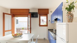Una cocina con un refrigerador blanco, armarios azules y una mesa de comedor con sillas.