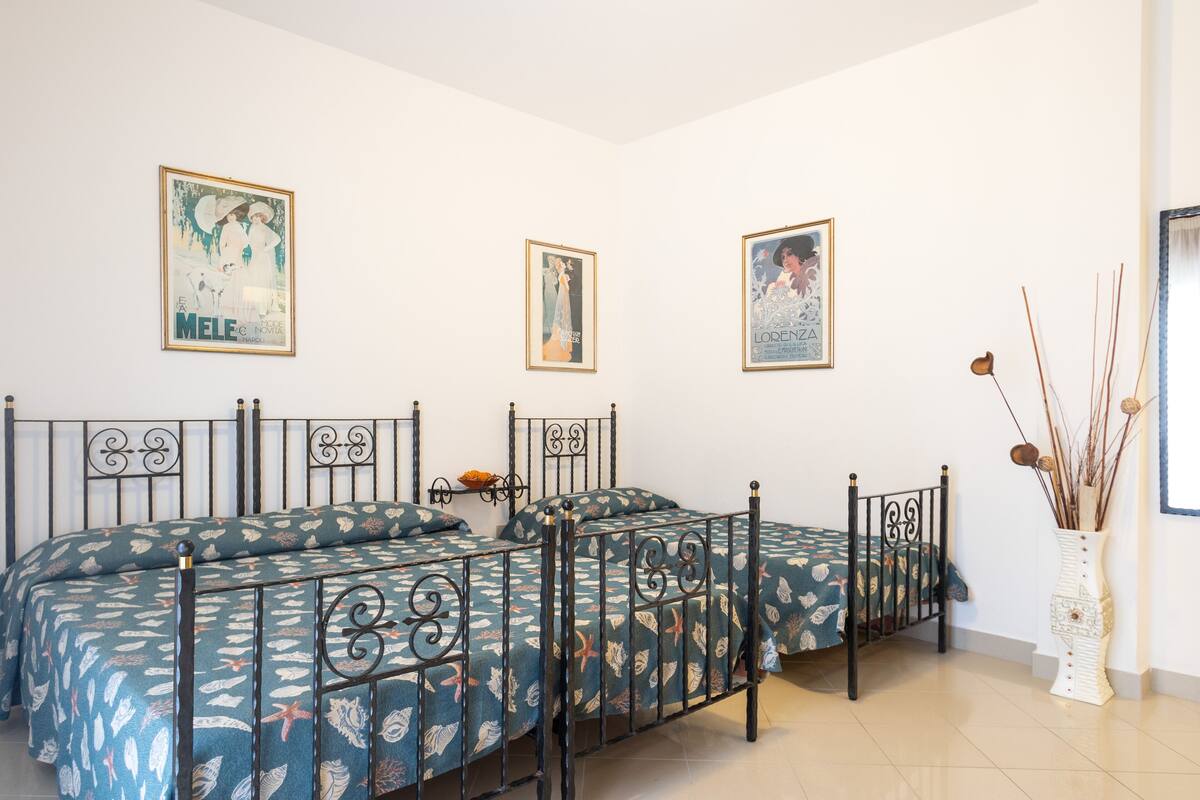 A bedroom with a bed, a nightstand, and a vase with decorative branches.