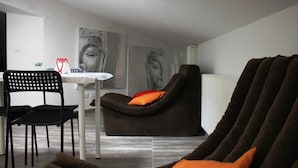Una sala de estar moderna con un sillón reclinable marrón, una mesa de comedor con sillas y arte abstracto en las paredes.