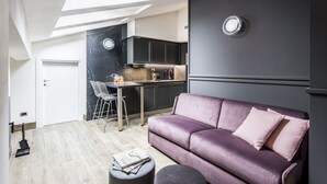 A modern living room with a sofa, a coffee table, and a dining area with a chair and table.