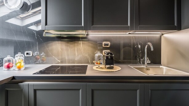 A modern kitchen with dark cabinetry, a stainless steel sink, and a built-in stove.