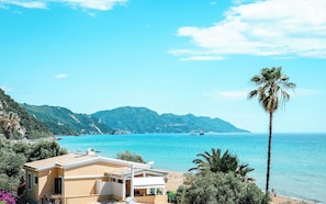 Una propiedad costera con vistas al mar, una cadena montañosa y una palmera.