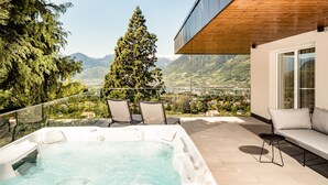 A hot tub on a balcony with a view of mountains and a town. - Chalet Penthouse – Schenna Chalet (Schenna)