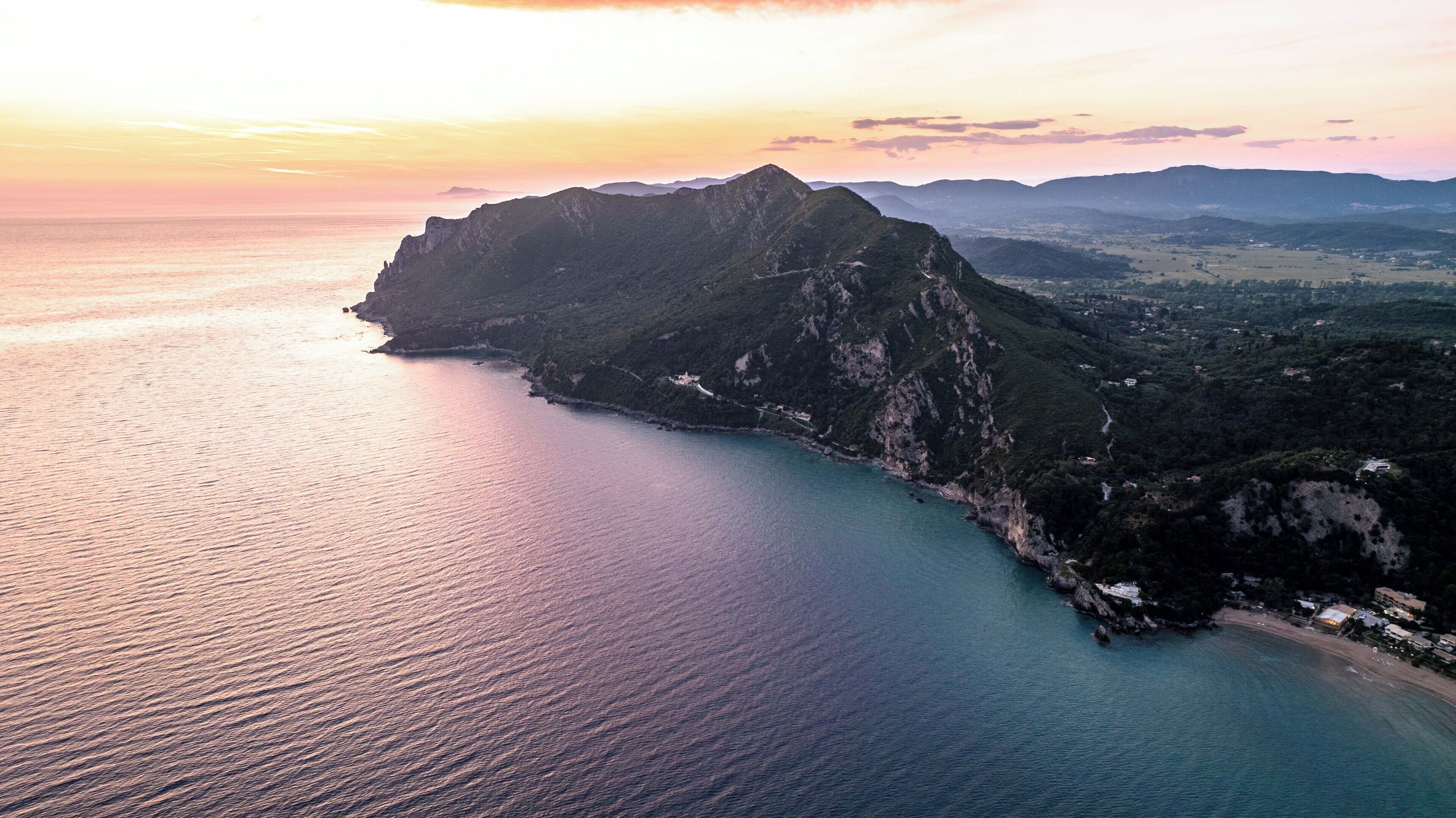 A coastal landscape with a prominent mountain, a beach, and a valley.