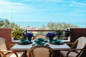 A balcony table with chairs, potted plants, and a view of the sea.