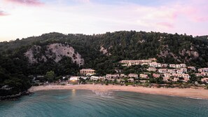 Un pueblo costero con edificios en una ladera, una playa y aguas azules cristalinas.