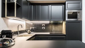 Una cocina moderna con armarios oscuros, un microondas de acero inoxidable y un protector contra salpicaduras de mármol.