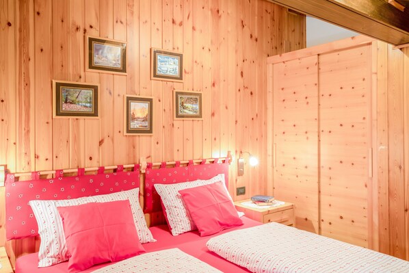 Una stanza in legno con un letto, comodini e quadri appesi al muro.