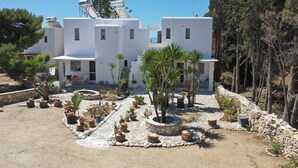 A modern white building with multiple windows and a stone pathway with potted plants. - Kikis Refurbished Apartment a Veranda Dream (Paros)
