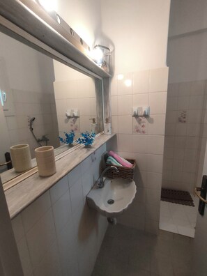 A bathroom with a sink, mirror, and two toilet paper holders.