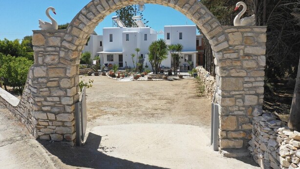 A stone archway with swan statues, leading to a white building complex with multiple rooms. - Kikis Refurbished Apartment a Veranda Dream (Paros)