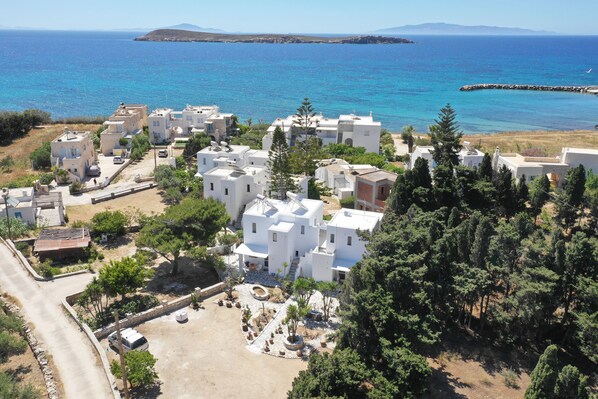 A coastal residential area with white buildings, a paved courtyard, and a view of the sea.