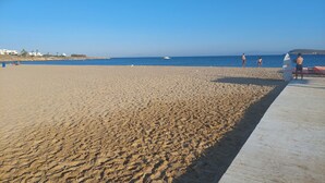 A sandy beach with a clear blue sky, a wooden walkway, and a few people. - Kikis Refurbished Apartment a Veranda Dream (Paros)