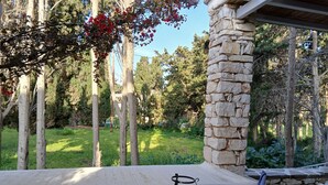 A stone pillar, a chair, and a small table with a bowl of fruit in a garden area. - Kikis Refurbished Apartment a Veranda Dream (Paros)