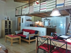 A cozy living area with a wooden sofa, a small table, and a kitchen in the background.