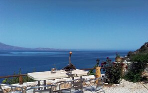 A table with chairs overlooking a coastal view. - Apartment Over the sea Private Place to Swim (Platanias)