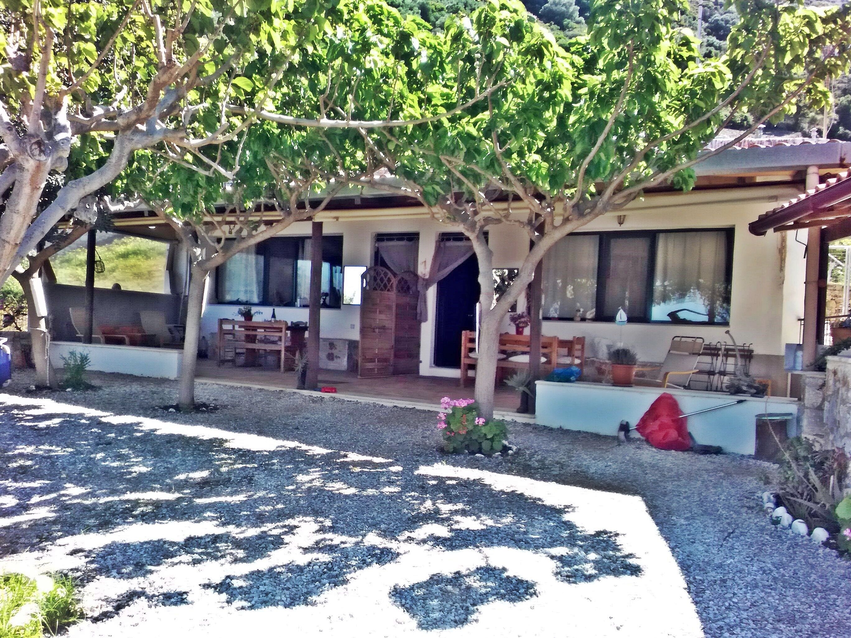 A house with a covered patio, outdoor seating, and a garden area.