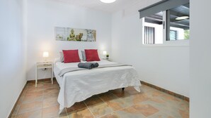 A bedroom with a bed, two bedside tables, a window, and a ceiling light. - Modern Apartment Casa Amanecer 1 with Pool, Terrace & Wi-Fi; Parking Available (Macher)