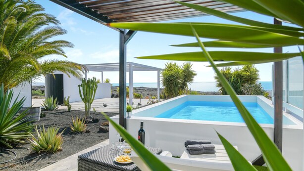 A modern outdoor pool area with a view of the sea, surrounded by tropical plants and a pergola. - Modern Apartment Casa Amanecer 1 with Pool, Terrace & Wi-Fi; Parking Available (Macher)