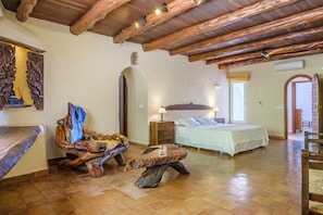 A room with a bed, wooden furniture, a wooden ceiling, and a tiled floor.