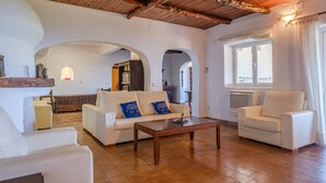 A spacious living area with a high wooden ceiling, white walls, and a central coffee table. - Air-Conditioned Villa with Sea View, Salty Pool, Terraces & Wi-Fi; Parking Available (Siesta - Santa Eulalia del Río)