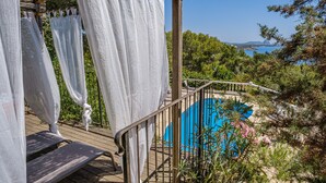 A wooden deck with a view of a blue pool and greenery. - Air-Conditioned Villa with Sea View, Salty Pool, Terraces & Wi-Fi; Parking Available (Siesta - Santa Eulalia del Río)