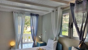 Une chambre d’hôtel avec deux lits, une table de chevet avec une lampe et une vue sur la verdure.
