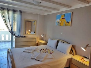 A hotel room with a bed, a bedside table, a nightstand, a mirror, and a painting on the wall.