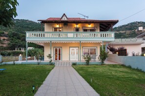 Une maison à deux étages dotée d’un balcon, d’une porte d’entrée et d’un chemin menant à l’entrée.