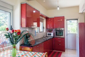 A modern kitchen with red cabinets, a microwave, an oven, and a dining area with a table and chairs.