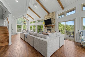 A spacious living room with a stone fireplace, large windows, and a wooden ceiling. - Modern Home w/private hot tub, game room, & Amazing VIEWS (Galena)
