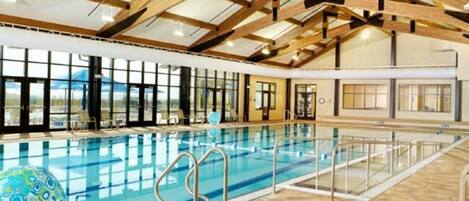 An indoor swimming pool with a high ceiling and large windows.