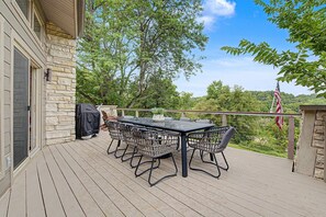 A covered outdoor deck with a table and chairs, a grill, and an American flag. - Modern Home w/private hot tub, game room, & Amazing VIEWS (Galena)