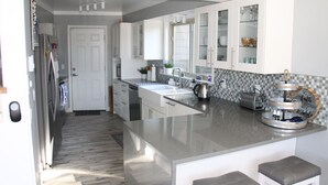 A modern kitchen with a large island, white cabinetry, and a checkered backsplash. - Modern Home w/private hot tub, game room, & Amazing VIEWS (Galena)