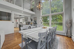 A spacious kitchen with a dining area, large windows, and a view of greenery. - Modern Home w/private hot tub, game room, & Amazing VIEWS (Galena)