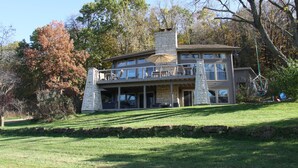 A multi-story house with a stone facade, large windows, and a covered patio area. - Modern Home w/private hot tub, game room, & Amazing VIEWS (Galena)
