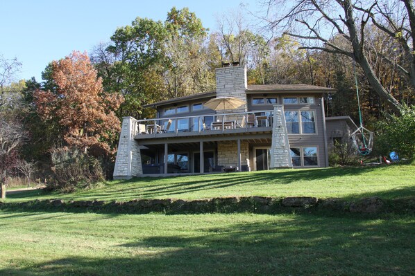 A multi-story house with a stone facade, large windows, and a covered patio area.