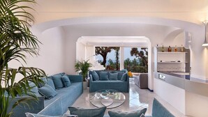 A modern living room with a sectional sofa, a coffee table, and a kitchen area with shelves.