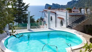 A swimming pool with a view of the sea and mountains.