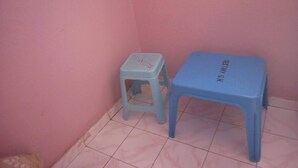 A small room with a pink wall, a blue stool, and a blue table. - Desmak Hotel (Isiolo)