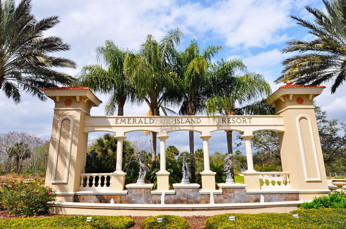 A sign with the text 'Emerald Island Resort' surrounded by palm trees and greenery.