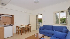 A compact living space with a kitchenette, dining area, and a blue sofa. - Manoleas Villas- Apartment 1 (West Mani)