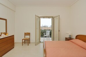 A bedroom with a bed, a dresser, a chair, and a balcony door. - Manoleas Villas - Apartment 2 (West Mani)
