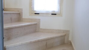 Beige marmeren trappen die leiden naar een vloer met een klein raam.