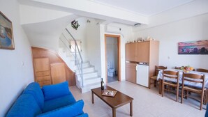 Un espace de vie compact comprenant un escalier menant à une salle de bain, une kitchenette et un coin repas avec une table et des chaises.