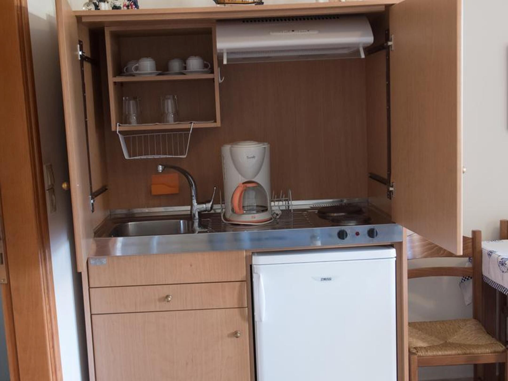 A compact kitchenette with a built-in stove, a coffee maker, and a small refrigerator.
