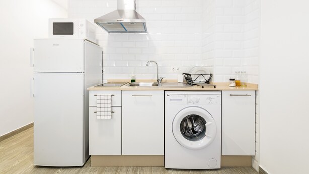 A modern kitchen with a refrigerator, microwave, sink, and washing machine. - Modern studio apartment - La Higuera 3 (Cadiz)