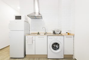 A modern kitchen with a refrigerator, microwave, sink, and washing machine.
